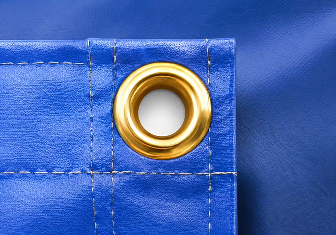 Close-up of metal eyelet installed on a reinforced PVC tarpaulin banner